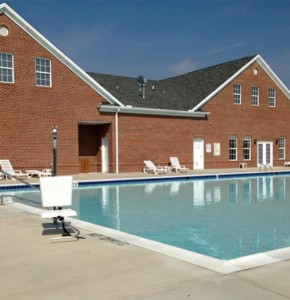 swimming pool surrounded by concrete with a brick building in the background